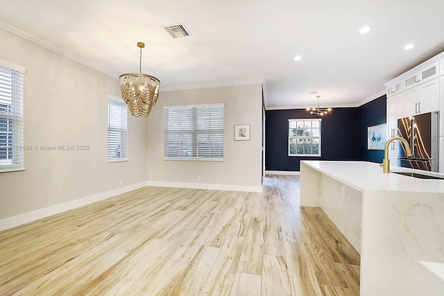 kitchen with white cabinets, high end fridge, hanging light fixtures, and an inviting chandelier