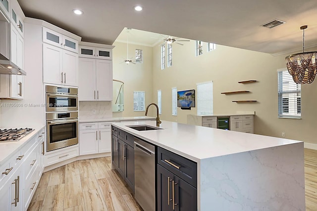 kitchen with white cabinetry, sink, hanging light fixtures, ceiling fan with notable chandelier, and appliances with stainless steel finishes