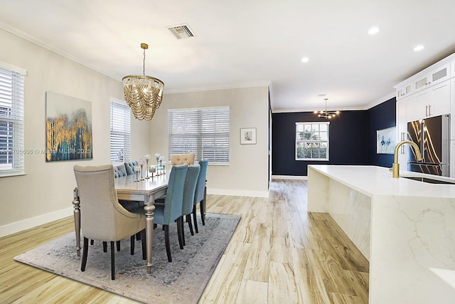 dining space featuring a notable chandelier, ornamental molding, and light hardwood / wood-style flooring