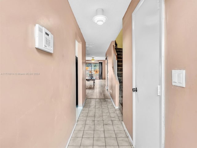 hallway featuring stairs, light tile patterned floors, and baseboards