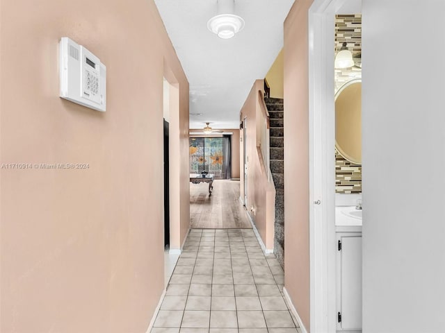 hallway with light tile patterned floors, stairway, and baseboards