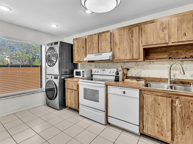 kitchen with stacked washer and clothes dryer, light countertops, a sink, white appliances, and under cabinet range hood