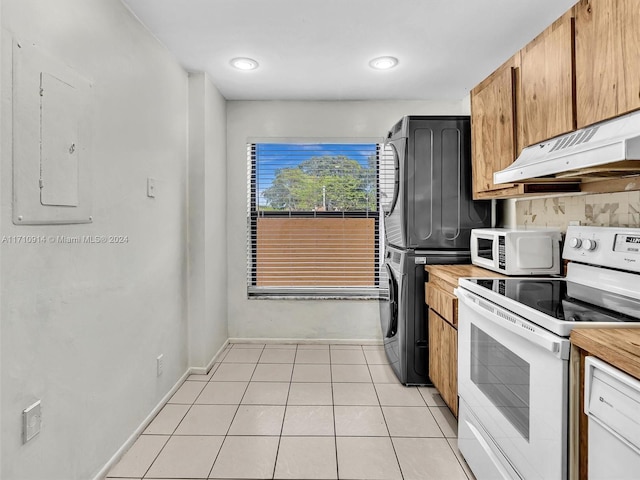 kitchen with under cabinet range hood, white appliances, light countertops, brown cabinets, and stacked washer and clothes dryer