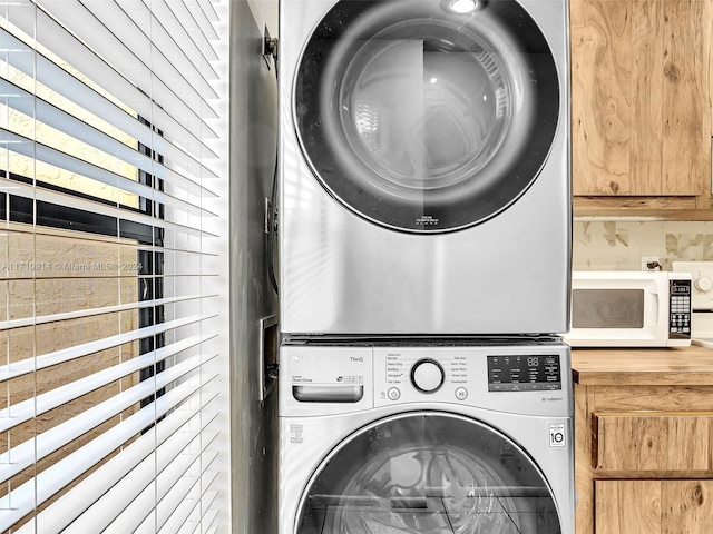 laundry room with stacked washer / dryer and cabinet space