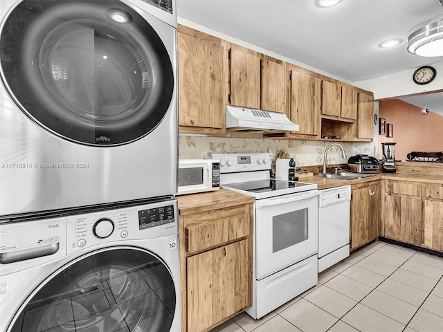 kitchen featuring under cabinet range hood, stacked washer and dryer, white appliances, a sink, and light countertops