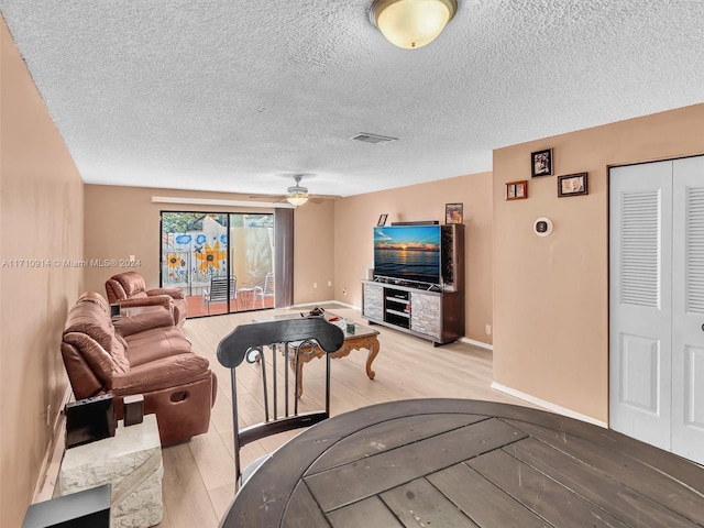 living area with visible vents, baseboards, a ceiling fan, a textured ceiling, and light wood-style floors