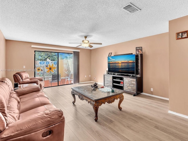 living room featuring a ceiling fan, light wood-style flooring, visible vents, and baseboards