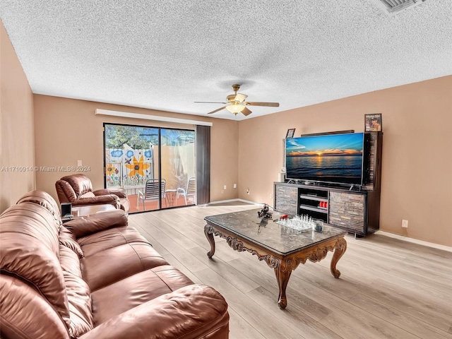 living room featuring a ceiling fan, light wood-type flooring, a textured ceiling, and baseboards