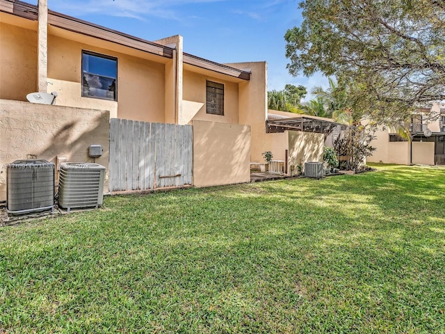 exterior space featuring central AC unit, a lawn, and stucco siding