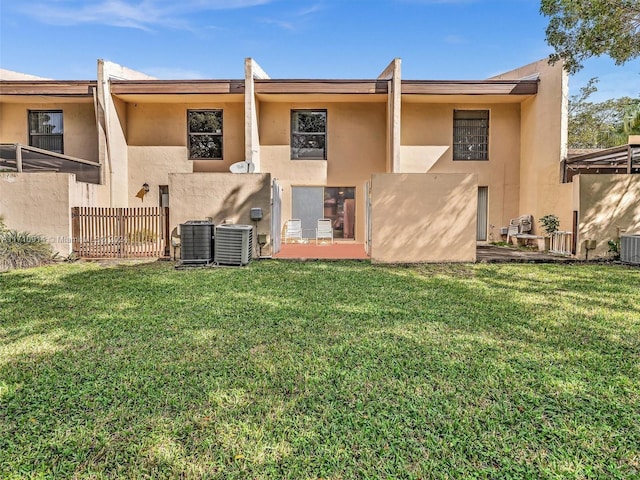 back of house featuring a yard, central AC unit, fence, and stucco siding