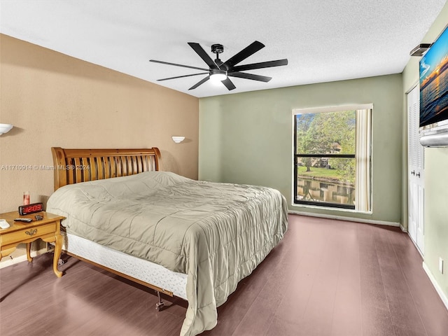 bedroom featuring a textured ceiling, wood finished floors, a ceiling fan, and baseboards