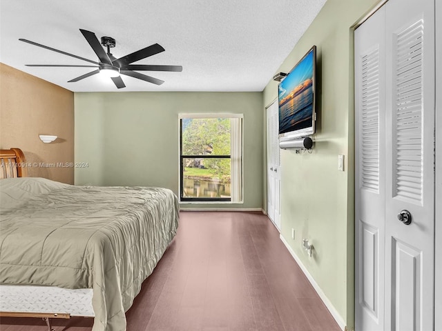 bedroom with a ceiling fan, a textured ceiling, baseboards, and wood finished floors