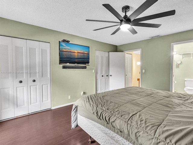 bedroom featuring a textured ceiling, visible vents, baseboards, multiple closets, and dark wood finished floors