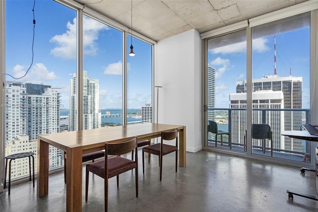 dining space with a wealth of natural light, a water view, and a wall of windows