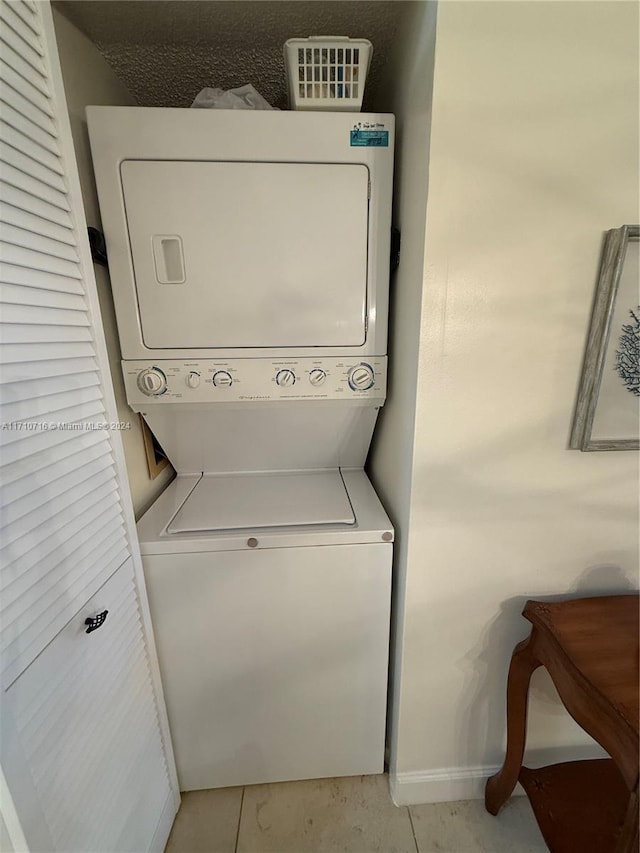 clothes washing area with light tile patterned floors and stacked washer / dryer