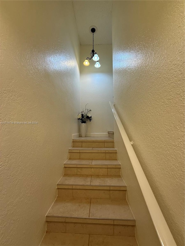 staircase with an inviting chandelier