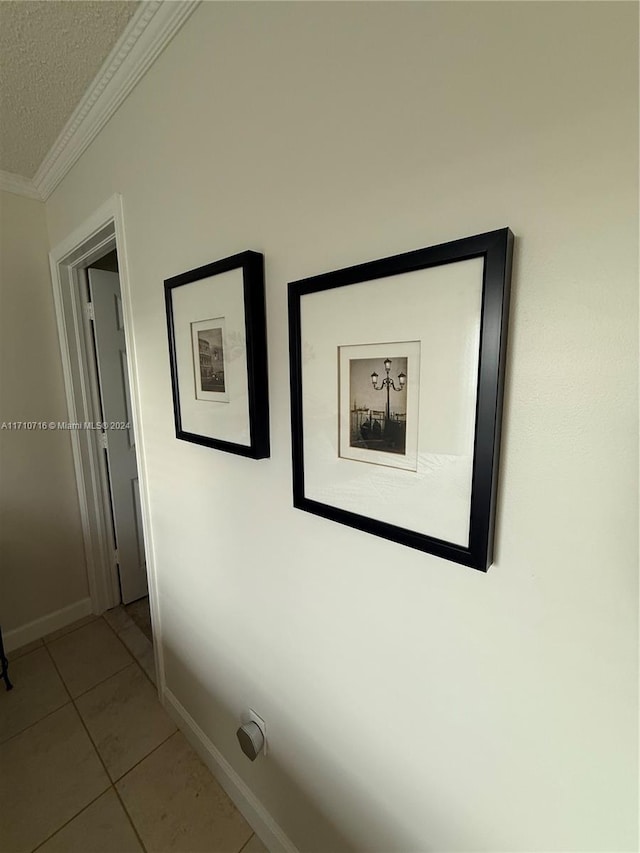 hallway featuring crown molding, light tile patterned flooring, and a textured ceiling