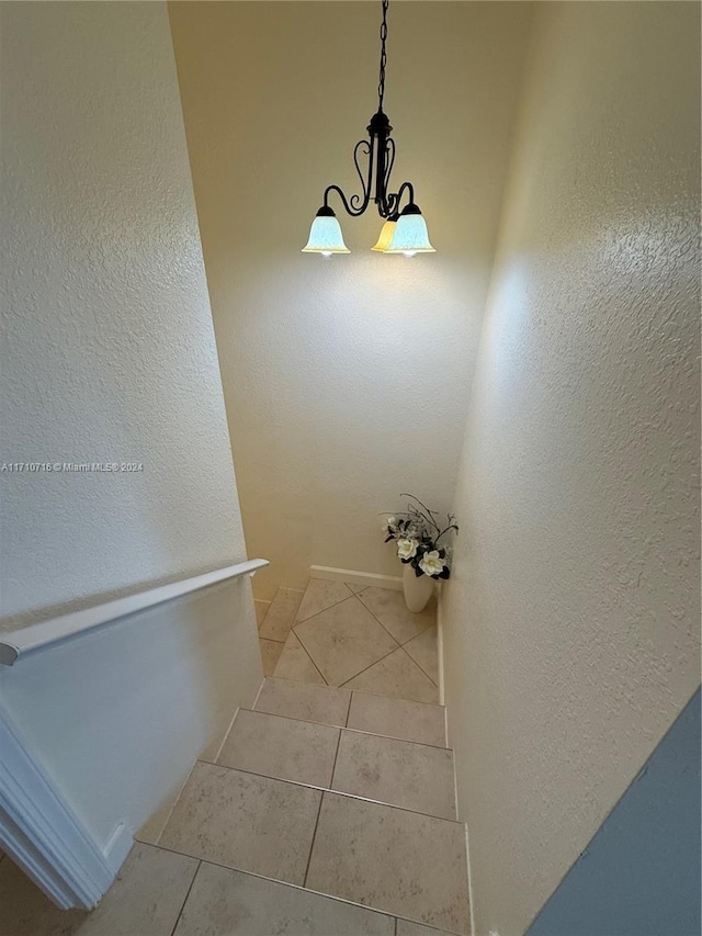 staircase featuring tile patterned flooring and a notable chandelier