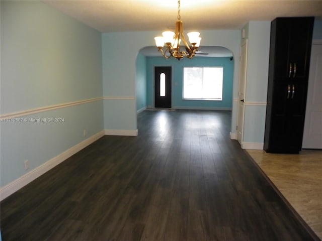 spare room featuring a chandelier and dark hardwood / wood-style flooring