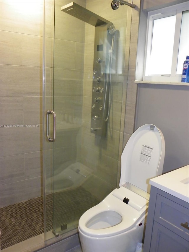 bathroom featuring toilet, an enclosed shower, and vanity