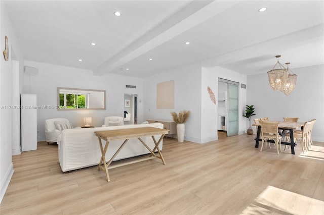 living room featuring beamed ceiling, light hardwood / wood-style floors, and an inviting chandelier