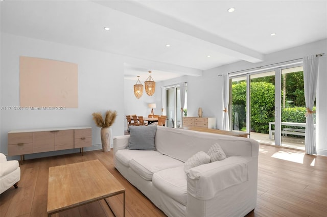 living room featuring beamed ceiling, an inviting chandelier, and light hardwood / wood-style flooring