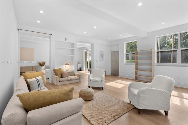 living room featuring beam ceiling and light hardwood / wood-style floors