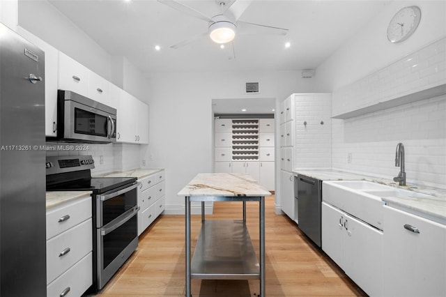 kitchen featuring light wood-type flooring, white cabinetry, backsplash, and appliances with stainless steel finishes