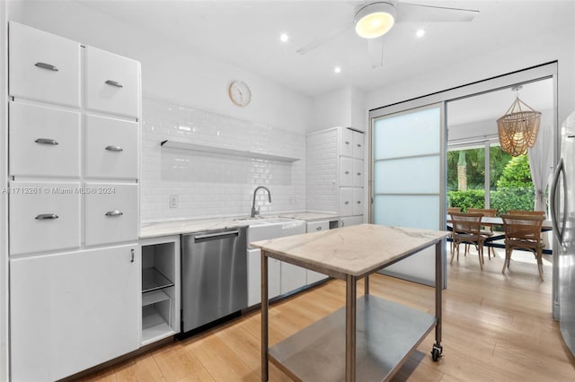 kitchen with backsplash, stainless steel appliances, sink, light hardwood / wood-style floors, and white cabinetry