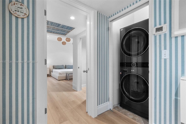 laundry area featuring light wood-type flooring and stacked washer / dryer