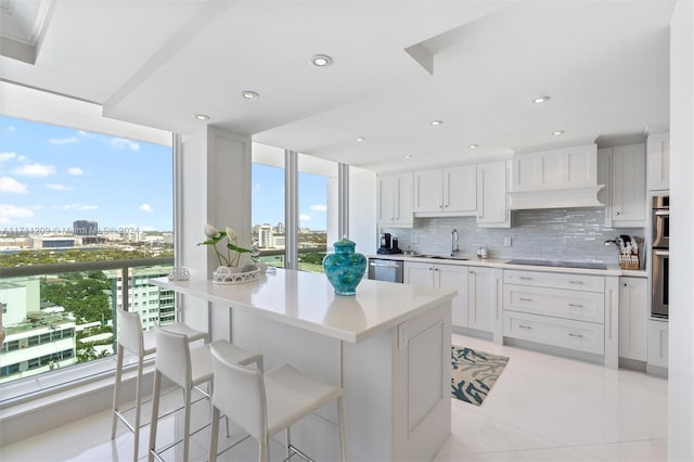 kitchen featuring backsplash, white cabinets, sink, appliances with stainless steel finishes, and a breakfast bar area