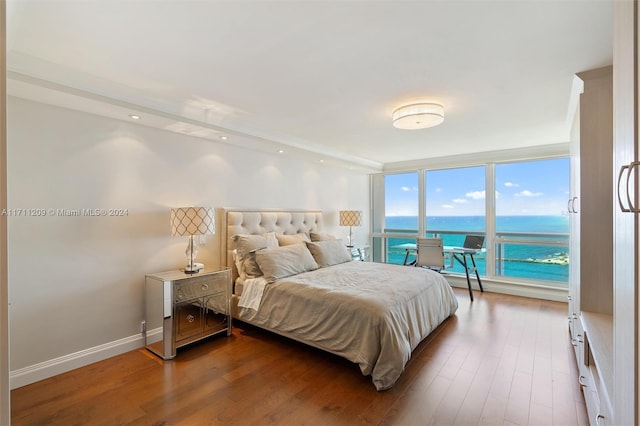 bedroom featuring expansive windows, a water view, and wood-type flooring