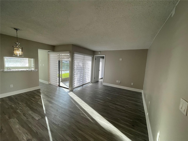 spare room with a notable chandelier, dark hardwood / wood-style flooring, and a textured ceiling