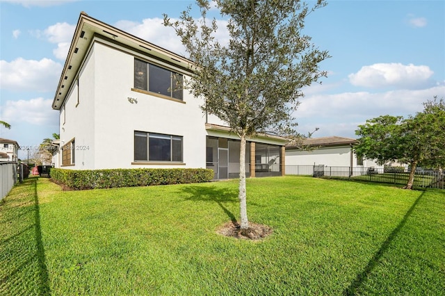 rear view of property featuring a sunroom and a yard