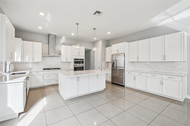 kitchen with wall chimney exhaust hood, stainless steel appliances, sink, decorative light fixtures, and a center island