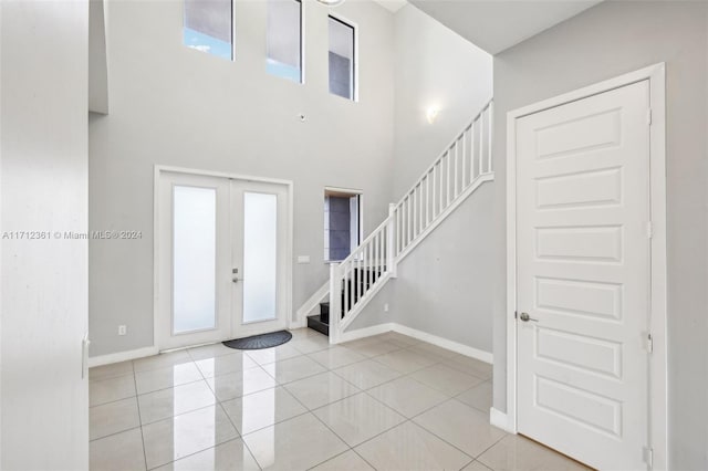 tiled entrance foyer with a towering ceiling and french doors