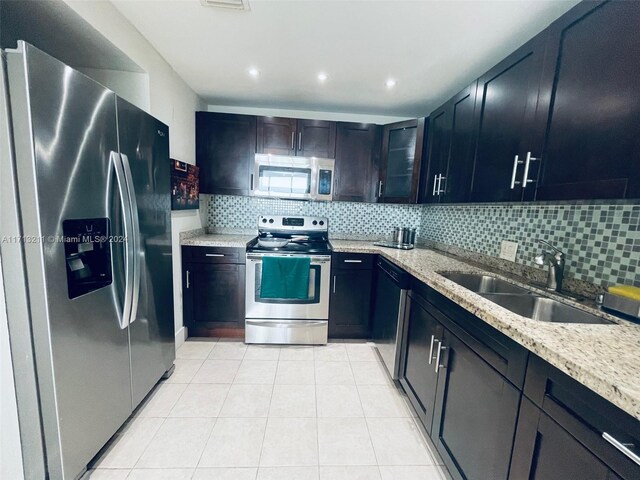 kitchen featuring sink, decorative backsplash, light tile patterned floors, appliances with stainless steel finishes, and light stone counters