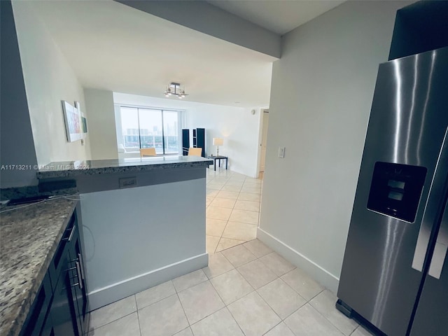 kitchen featuring kitchen peninsula, stainless steel refrigerator with ice dispenser, dark stone counters, and light tile patterned flooring