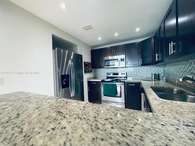 kitchen featuring backsplash, light stone counters, sink, and stainless steel appliances