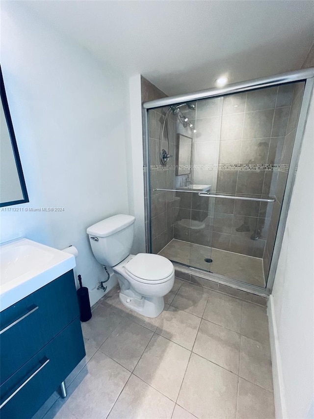 bathroom featuring tile patterned floors, vanity, toilet, and a shower with door