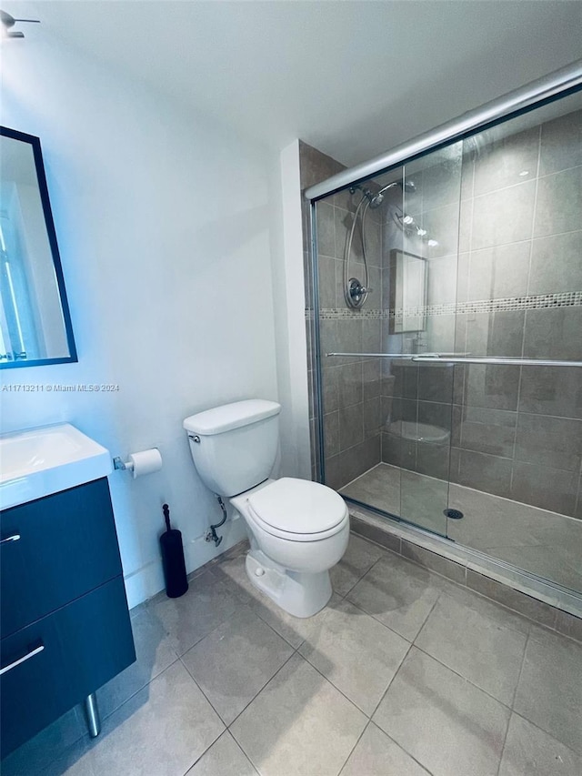 bathroom featuring tile patterned flooring, vanity, toilet, and an enclosed shower