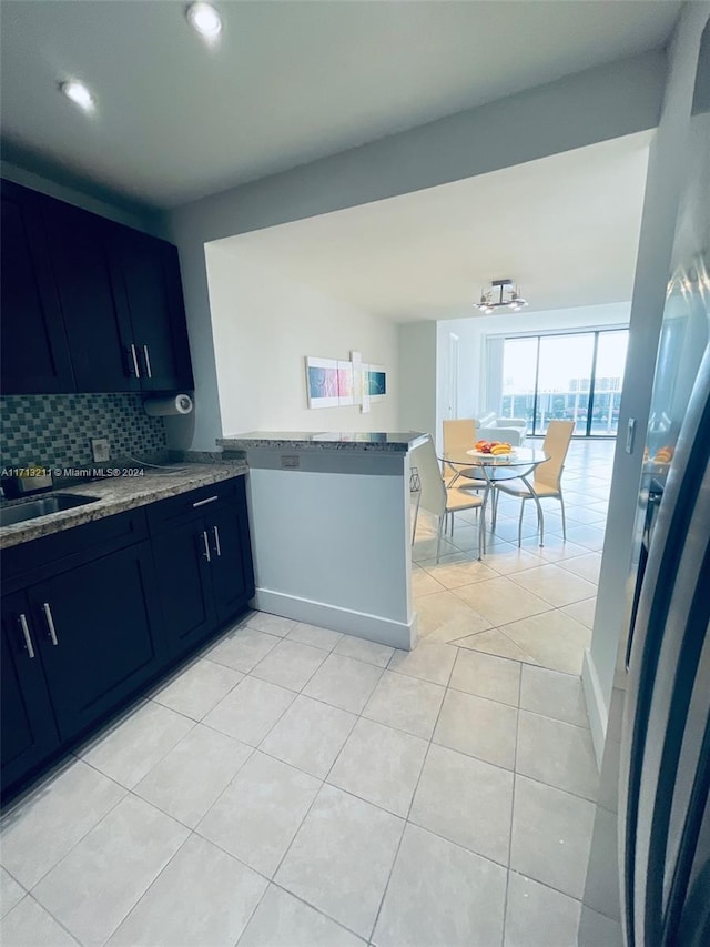 kitchen with stone counters, sink, kitchen peninsula, decorative backsplash, and light tile patterned flooring