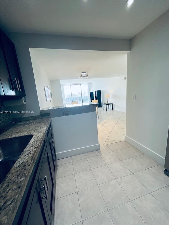 kitchen featuring kitchen peninsula, light tile patterned floors, and dark stone countertops