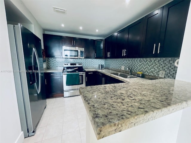 kitchen with backsplash, kitchen peninsula, sink, and appliances with stainless steel finishes