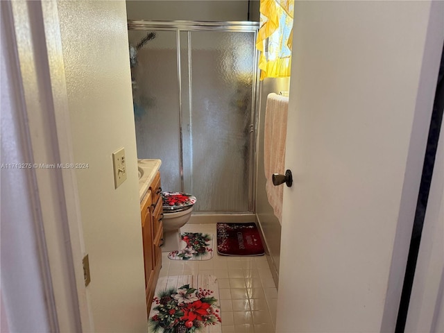 bathroom with tile patterned flooring, vanity, a shower with shower door, and toilet