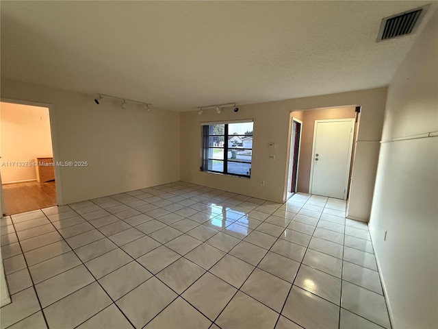 living room featuring a textured ceiling, light tile patterned floors, and visible vents
