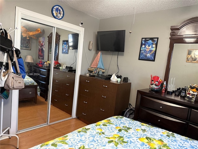 bedroom featuring a closet, light hardwood / wood-style floors, and a textured ceiling