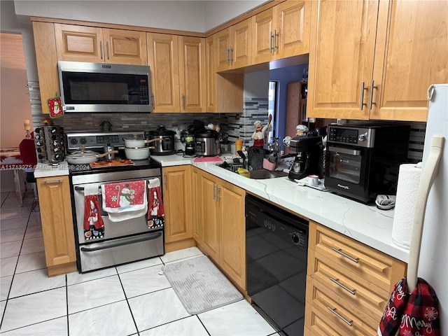 kitchen featuring light stone countertops, appliances with stainless steel finishes, backsplash, and light tile patterned flooring