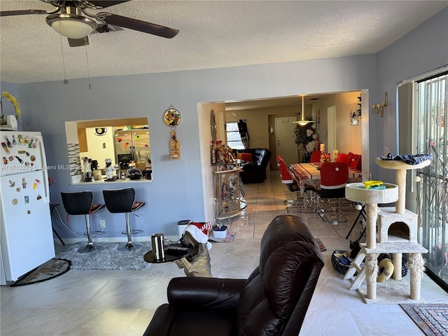 living room with ceiling fan and a textured ceiling