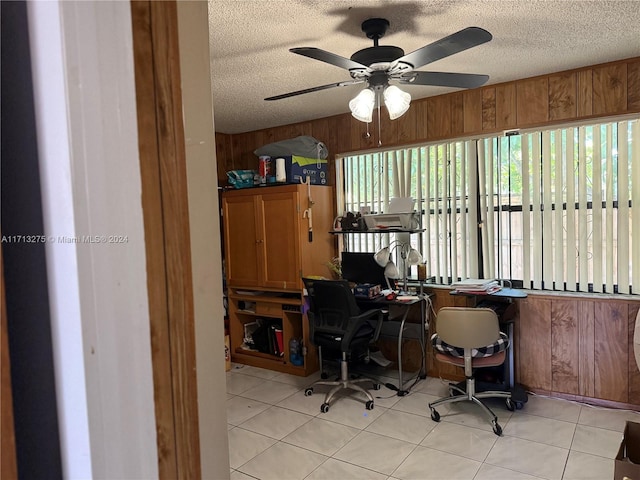 office featuring ceiling fan, wooden walls, light tile patterned floors, and a textured ceiling